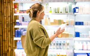 Mulher realizando compras e comparando as embalagens.